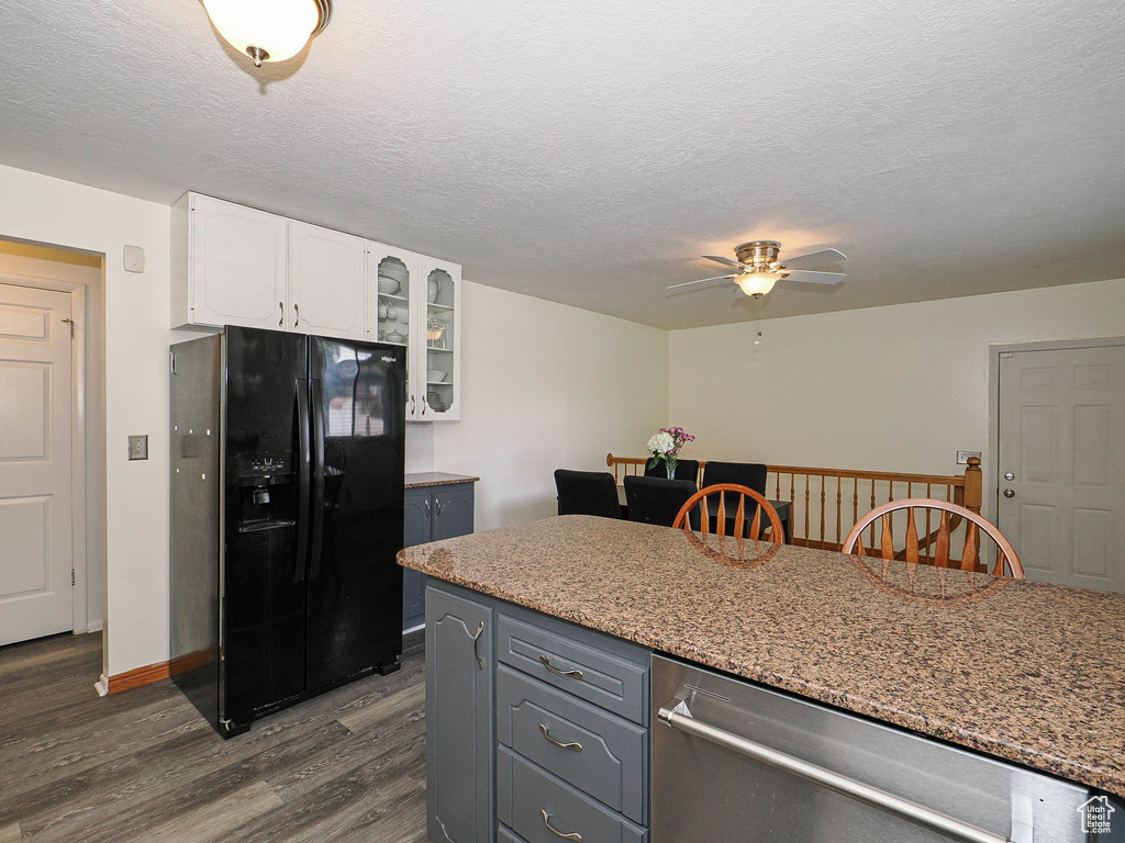 Kitchen featuring black fridge, stainless steel dishwasher, dark wood-type flooring, white cabinets, and a ceiling fan
