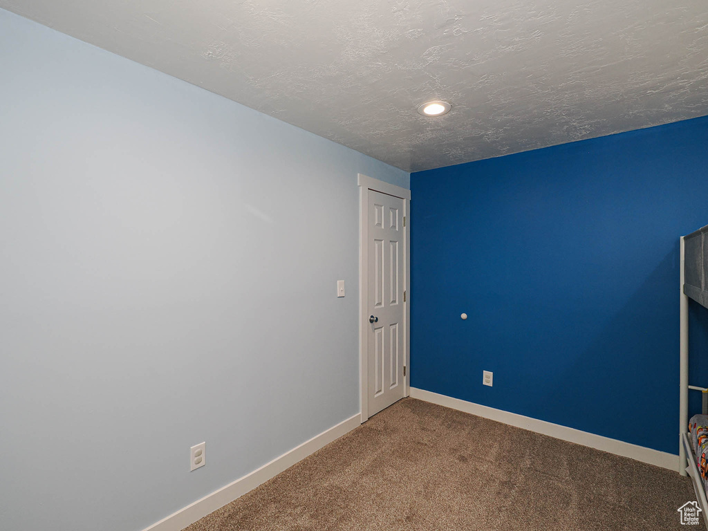 Empty room featuring baseboards, carpet, a textured ceiling, and recessed lighting