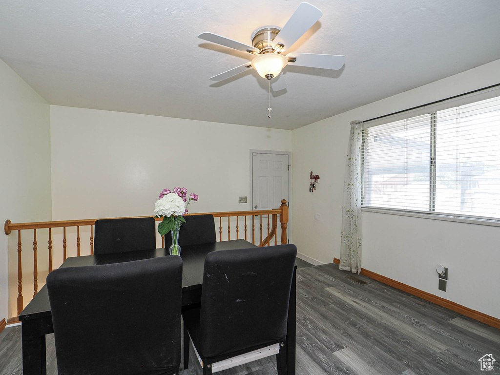 Dining space featuring dark wood-type flooring, ceiling fan, and baseboards