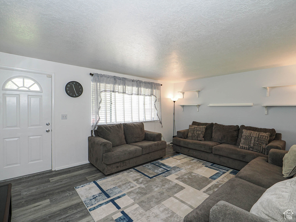 Living area featuring a textured ceiling, wood finished floors, and baseboards