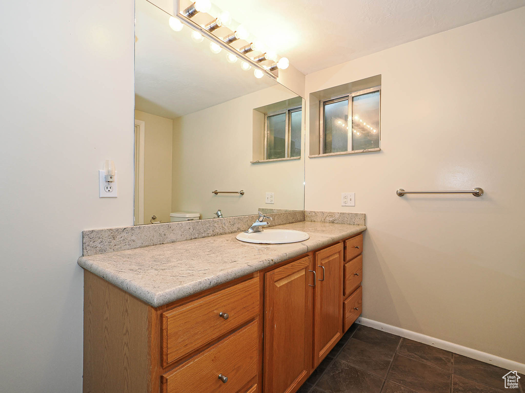 Bathroom featuring vanity, baseboards, and toilet