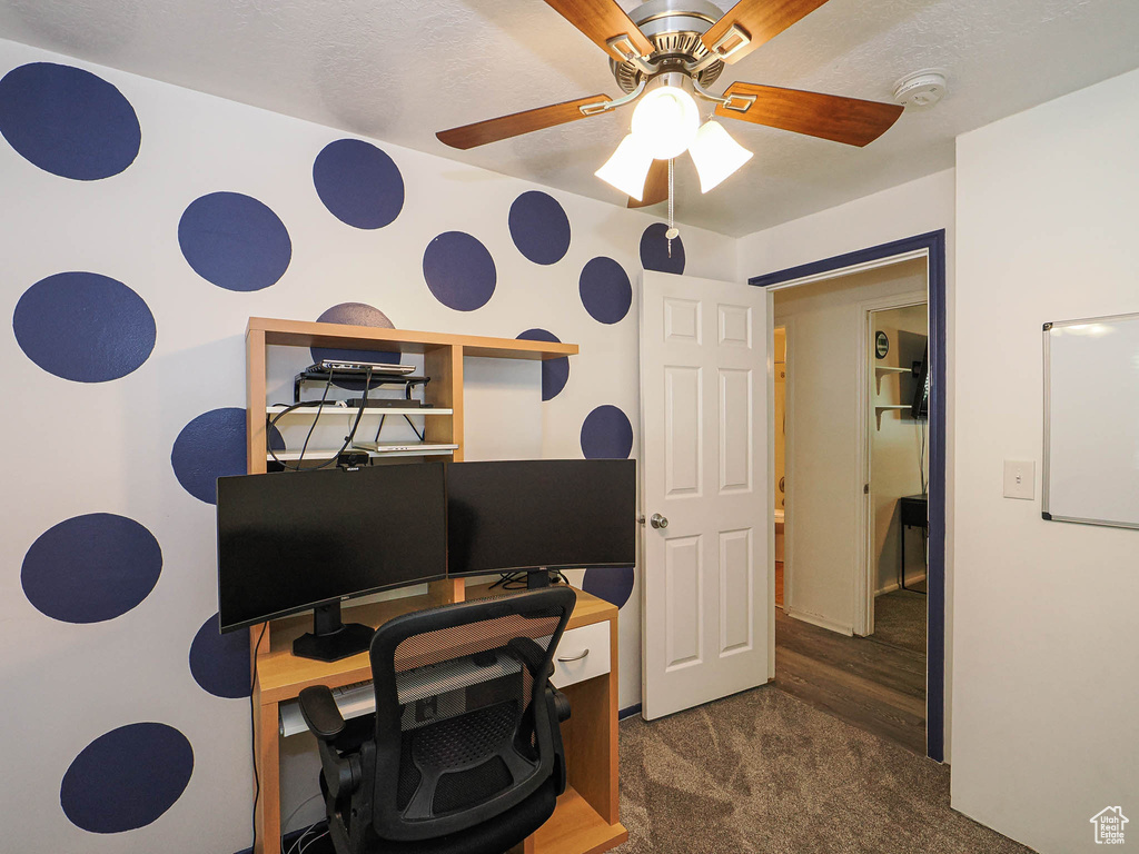Office area with dark carpet and a ceiling fan