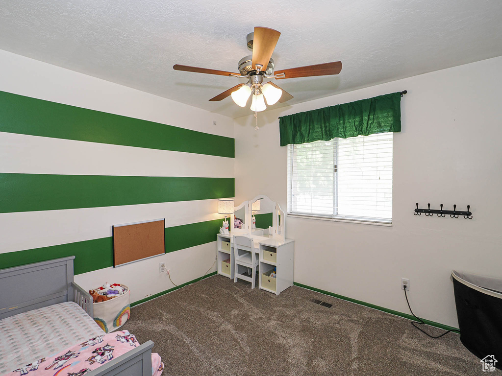 Carpeted bedroom with a ceiling fan and a textured ceiling