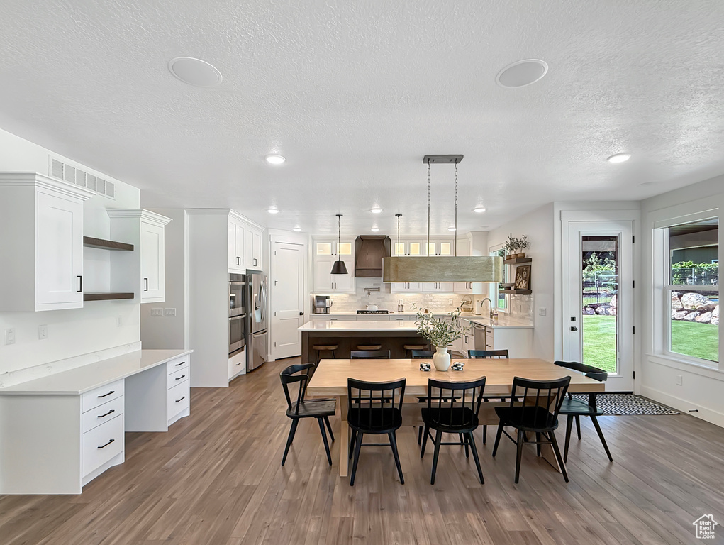 Dining area with wood finished floors, a textured ceiling, recessed lighting, and baseboards