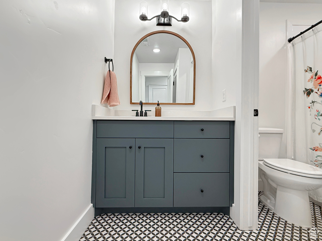 Bathroom with vanity, toilet, baseboards, and curtained shower