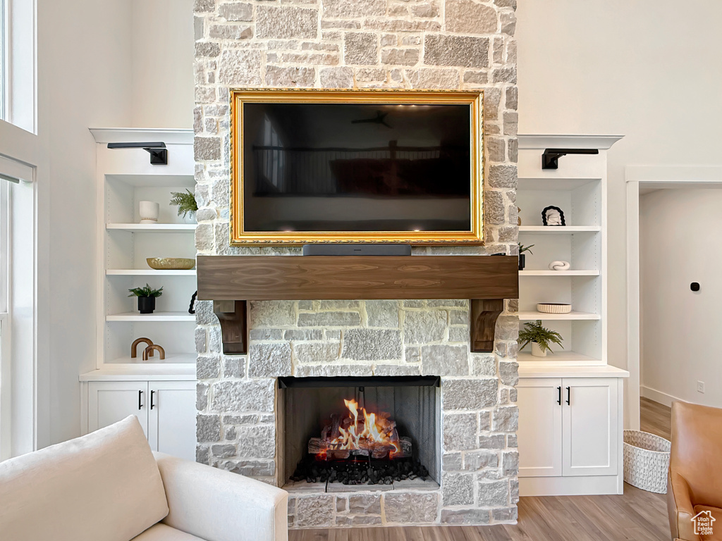 Detailed view of a stone fireplace, wood finished floors, and built in shelves