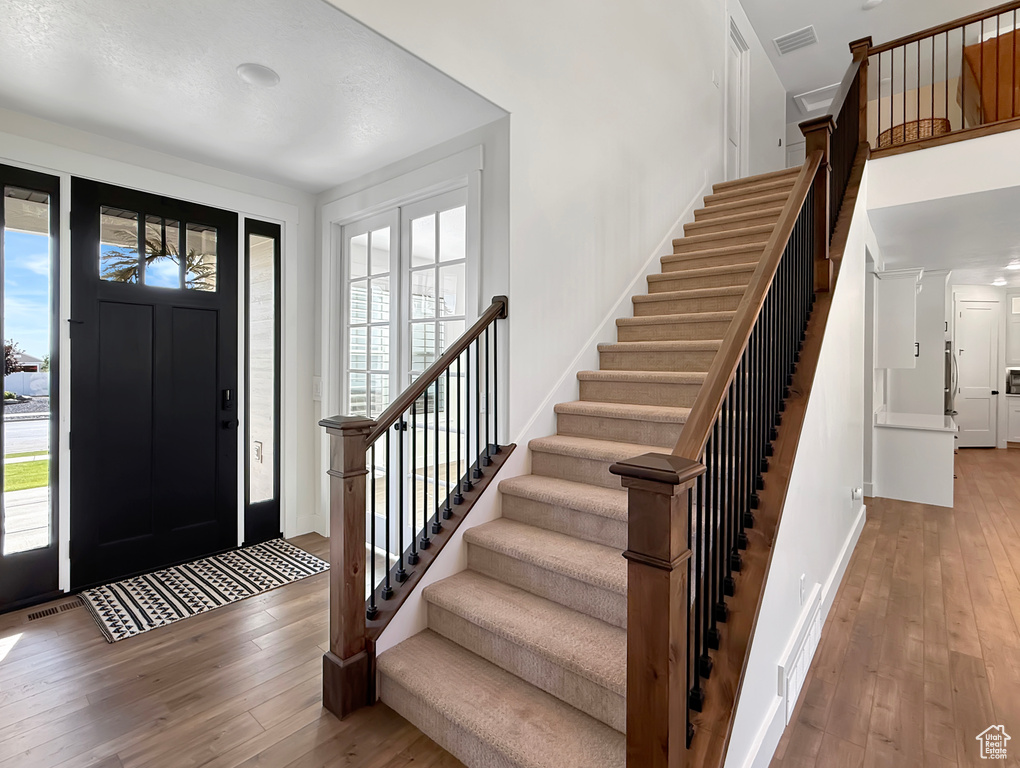 Entrance foyer with hardwood / wood-style flooring, plenty of natural light, and stairs