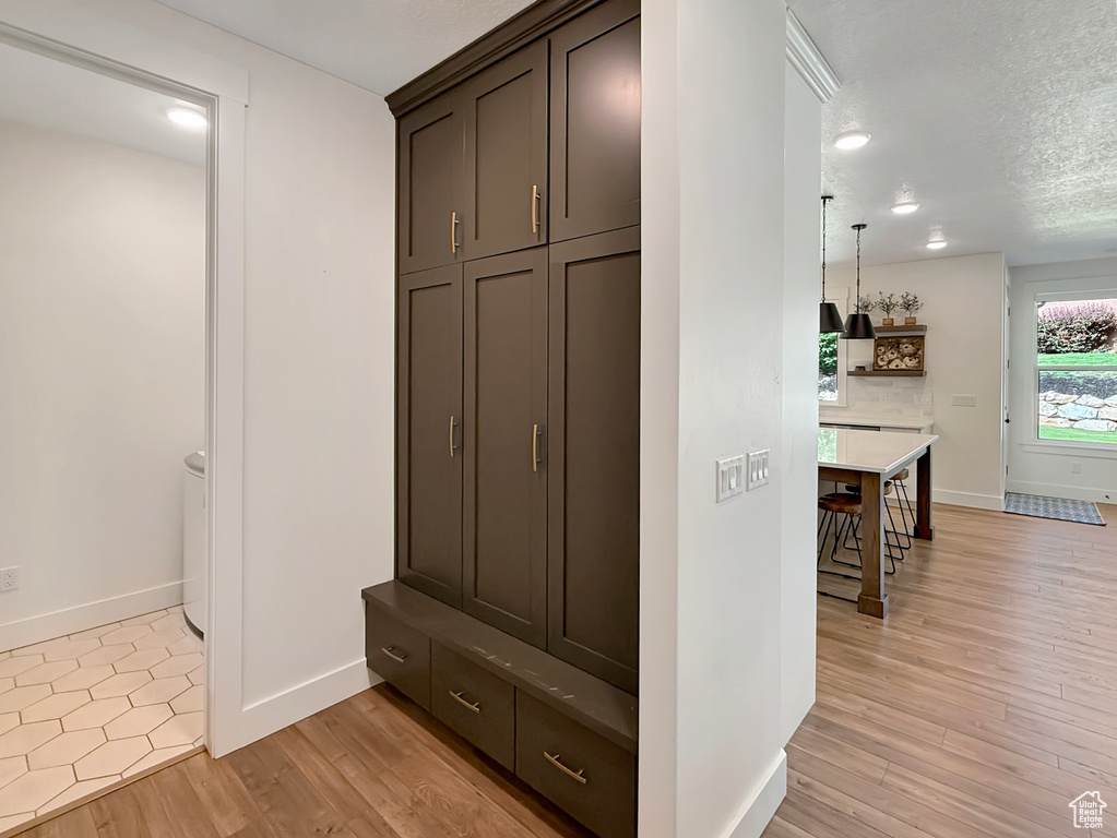 Mudroom featuring light wood-type flooring, baseboards, and a textured ceiling