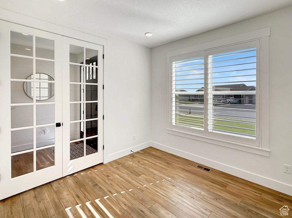 Unfurnished room featuring plenty of natural light, baseboards, and wood finished floors