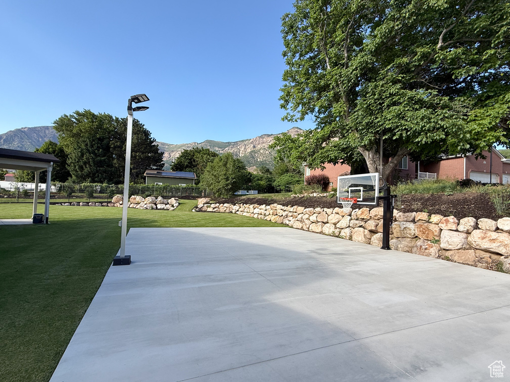 View of basketball court with a mountain view, a yard, and community basketball court