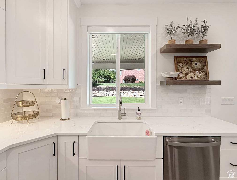 Kitchen with stainless steel dishwasher, a sink, tasteful backsplash, and open shelves