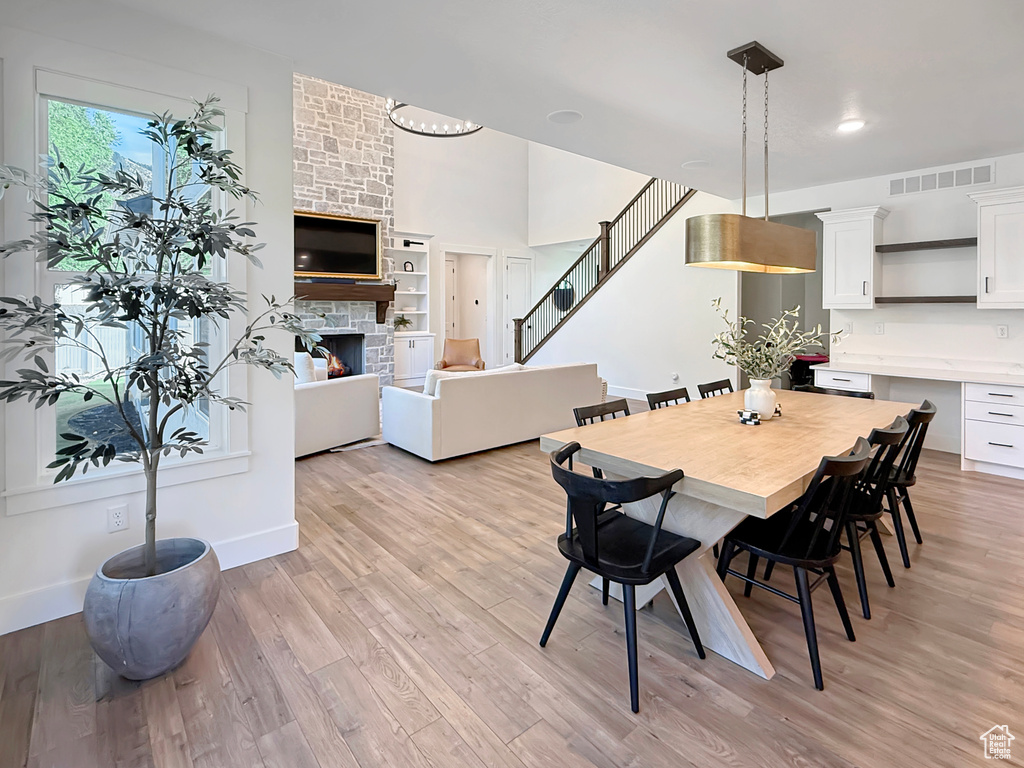 Dining space with a fireplace, light wood-type flooring, stairs, and baseboards