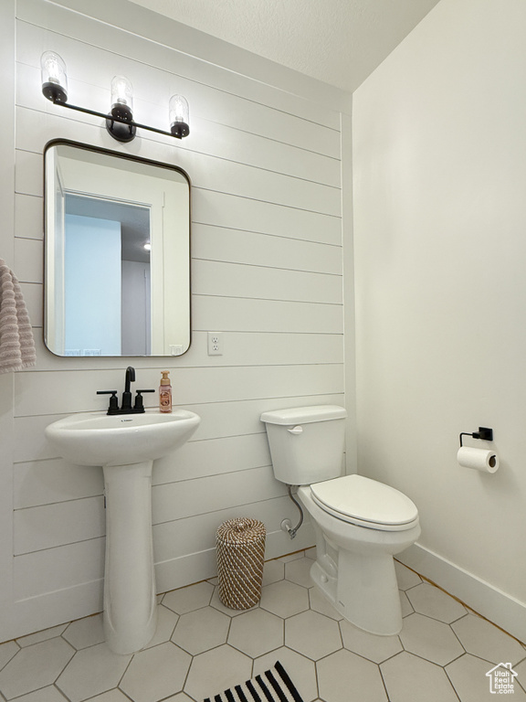 Half bathroom featuring toilet, tile patterned floors, and a sink