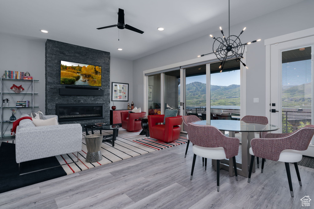 Dining area featuring wood finished floors, a chandelier, a fireplace, a mountain view, and recessed lighting