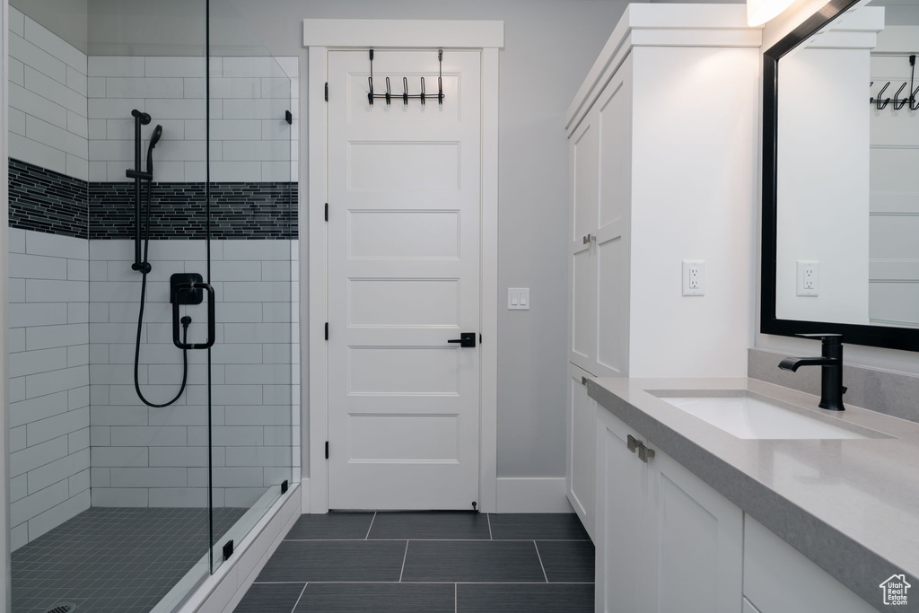 Bathroom with a stall shower, vanity, tile patterned flooring, and baseboards