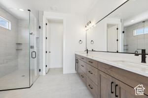 Bathroom with double vanity, a shower stall, and baseboards