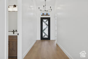 Foyer with light wood-type flooring, a chandelier, and baseboards