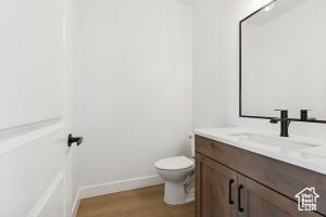 Bathroom with vanity, toilet, wood finished floors, and baseboards