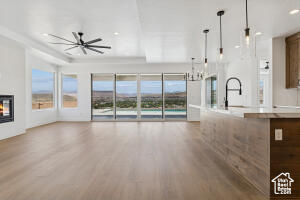 Unfurnished living room featuring wood finished floors, plenty of natural light, a ceiling fan, and a glass covered fireplace