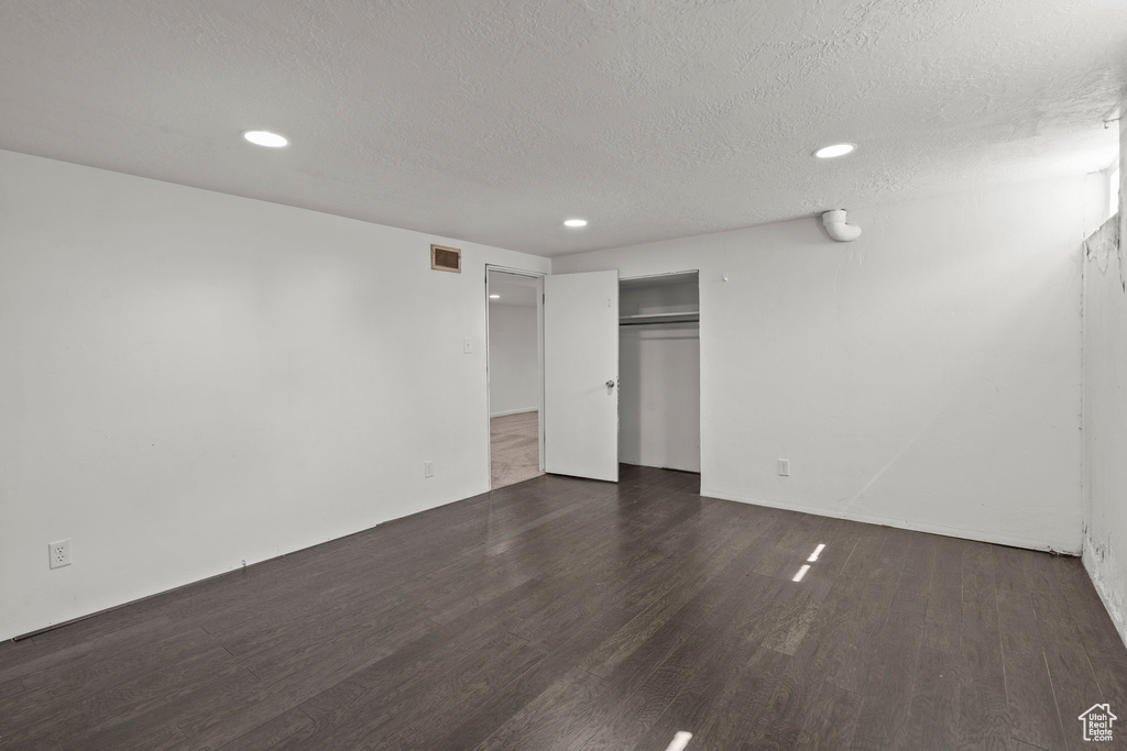 Unfurnished bedroom featuring dark wood-style floors, a textured ceiling, recessed lighting, and a closet