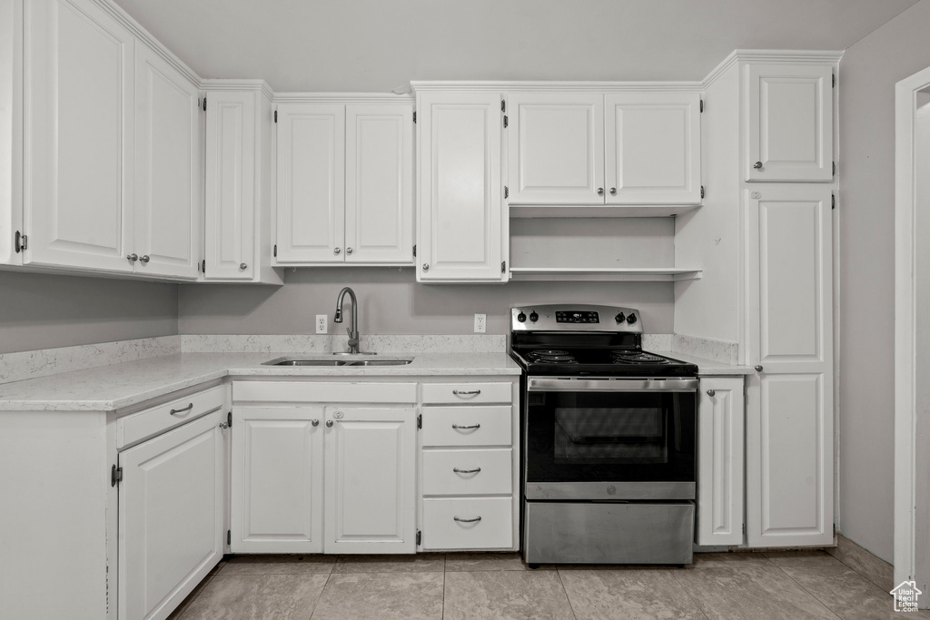 Kitchen featuring stainless steel electric range oven, a sink, white cabinets, and open shelves