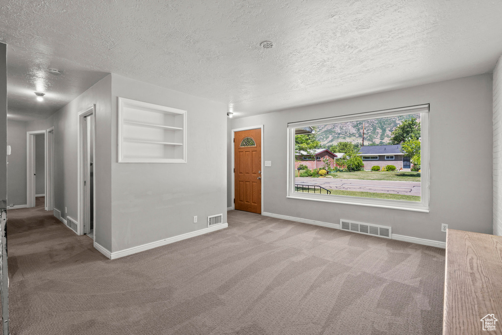 Spare room with carpet, a textured ceiling, and baseboards