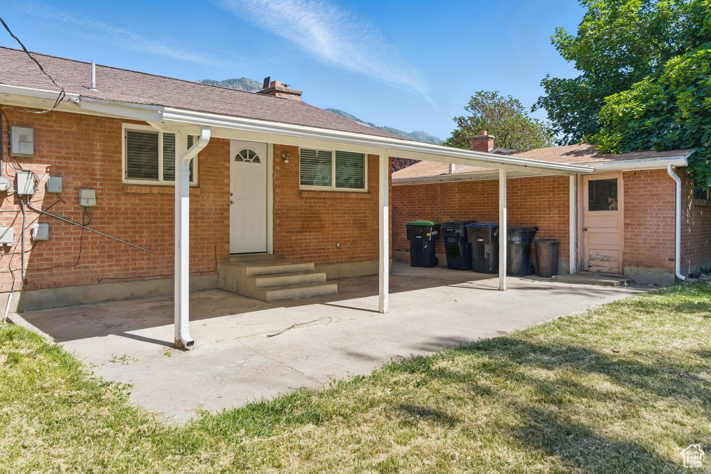 Back of property featuring a chimney, brick siding, a patio area, and a yard