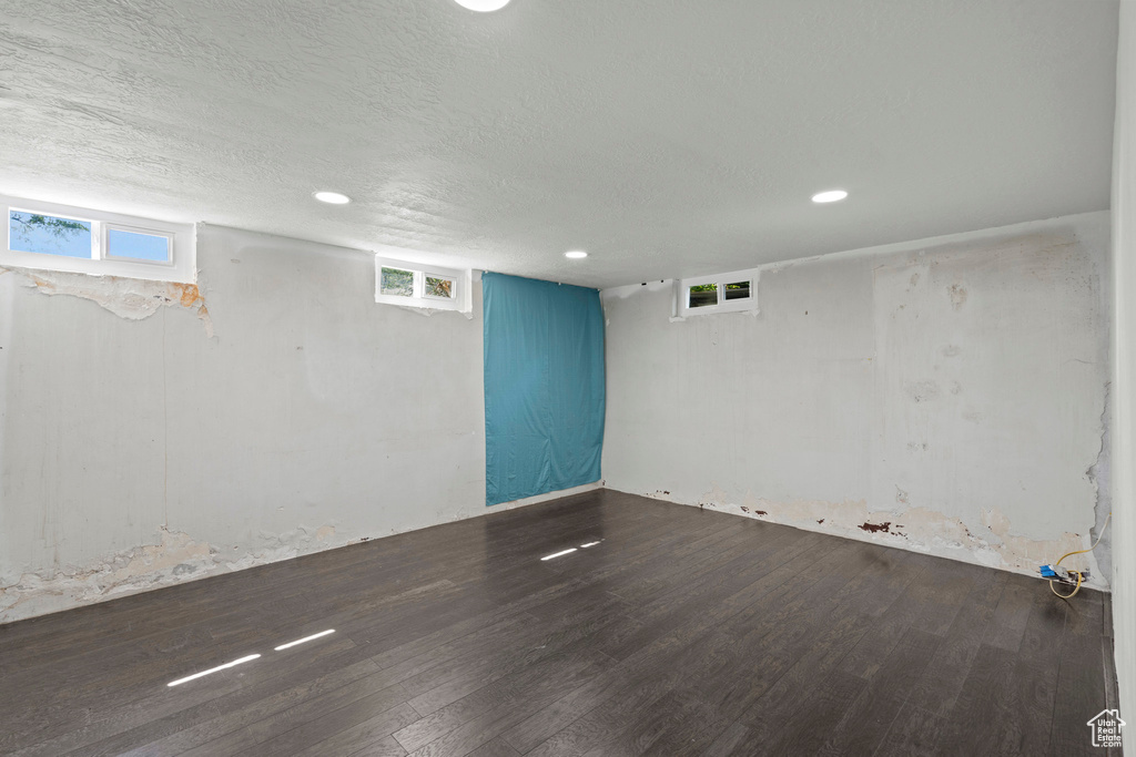 Basement with wood finished floors, plenty of natural light, recessed lighting, and a textured ceiling