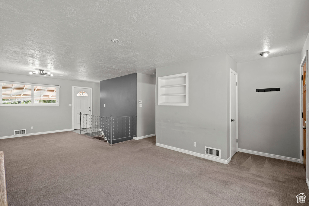 Carpeted entryway with a textured ceiling and baseboards