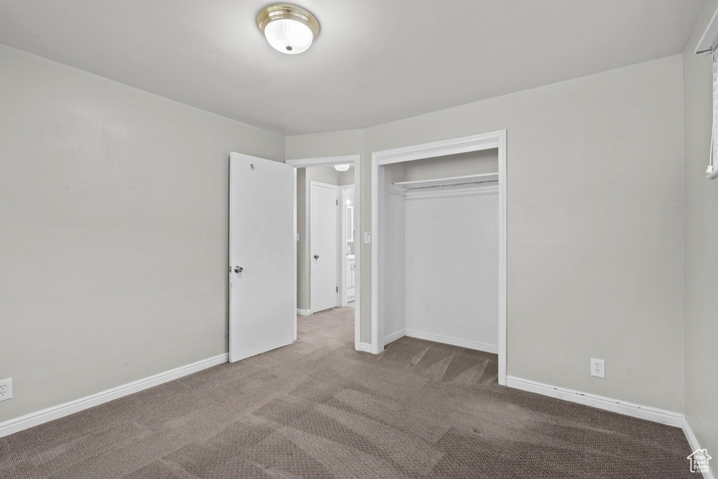 Unfurnished bedroom with carpet floors, a closet, and baseboards