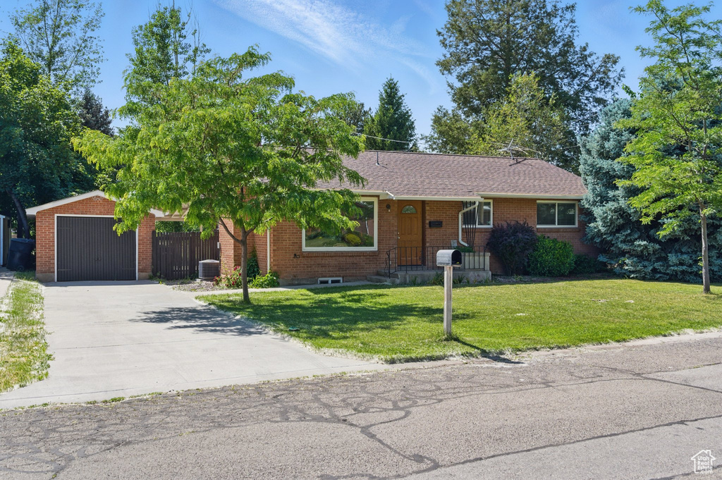 Ranch-style house with brick siding, concrete driveway, a front yard, and an outdoor structure