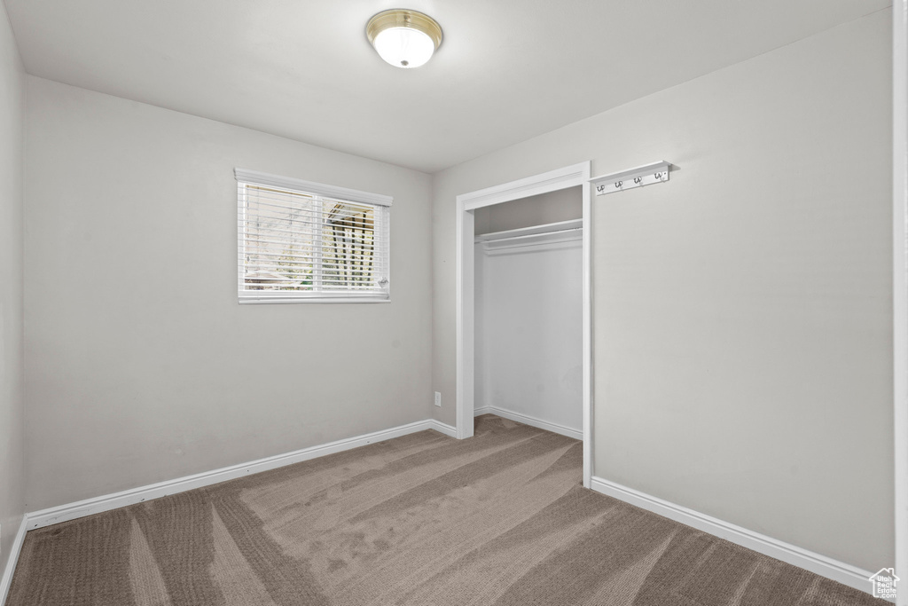 Unfurnished bedroom with a closet, carpet flooring, and baseboards
