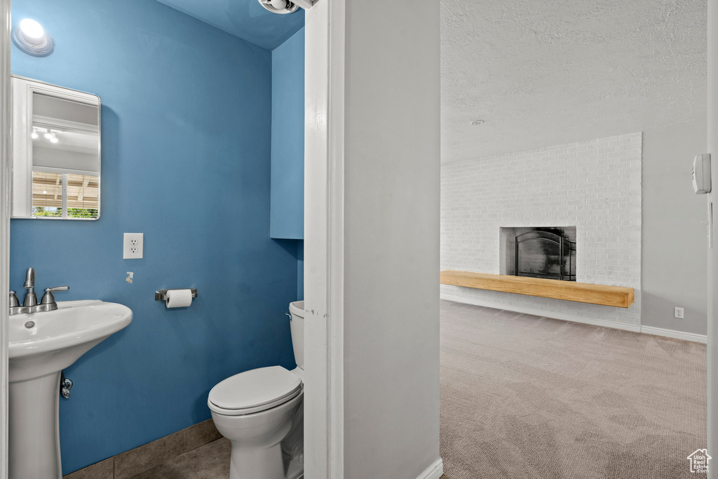 Bathroom featuring toilet, baseboards, a sink, and a fireplace