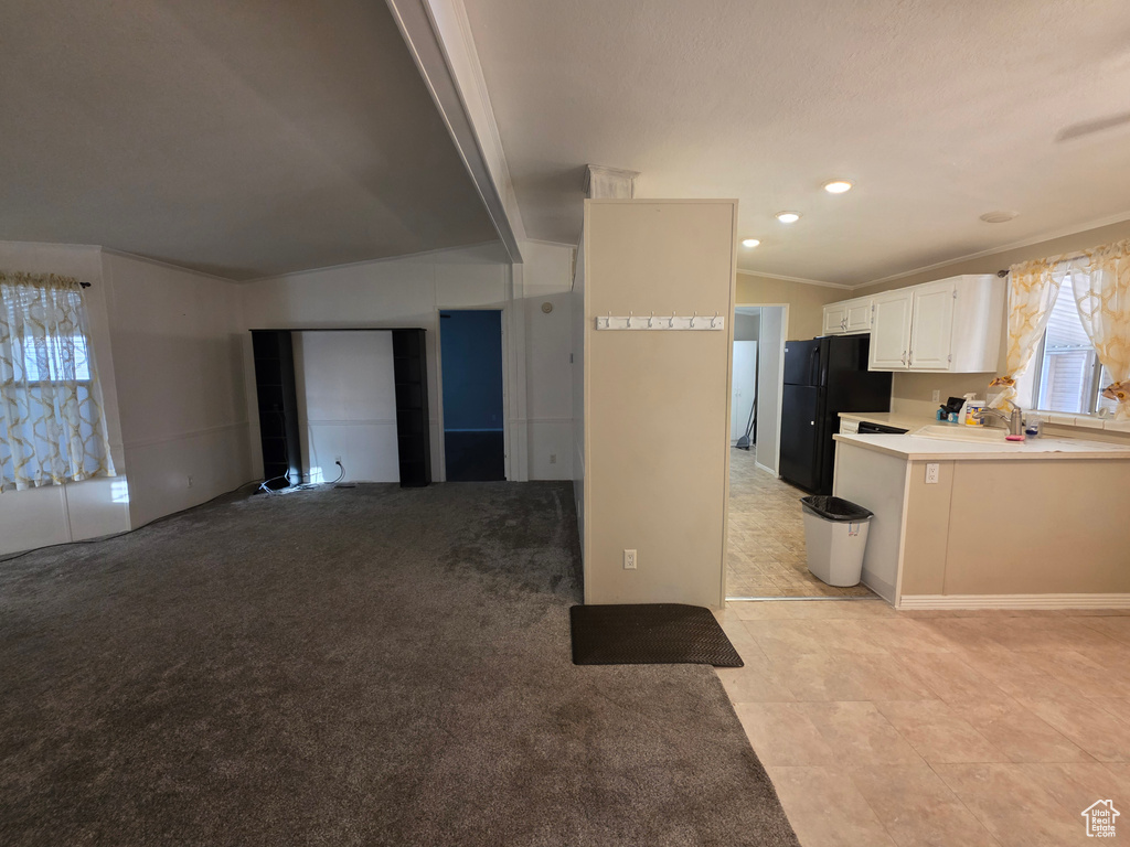 Kitchen with freestanding refrigerator, ornamental molding, white cabinetry, light countertops, and light tile patterned floors