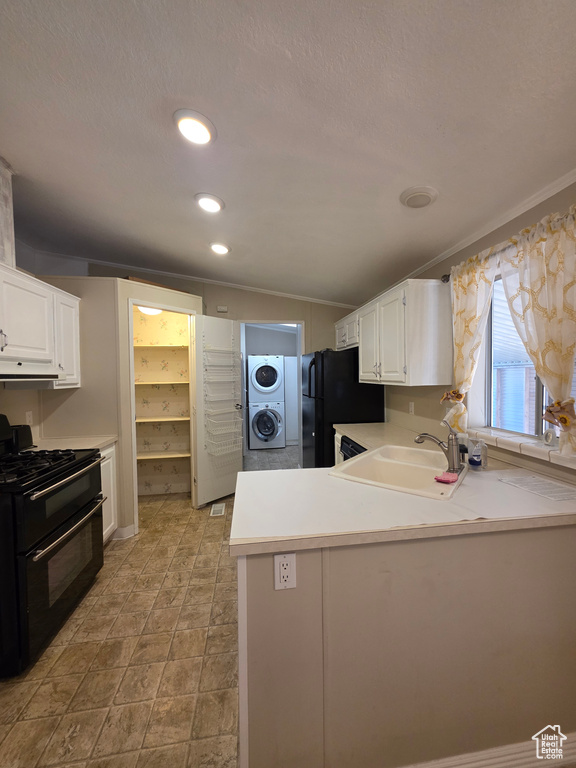 Kitchen featuring black appliances, a sink, estacked washer and dryer, white cabinets, and lofted ceiling