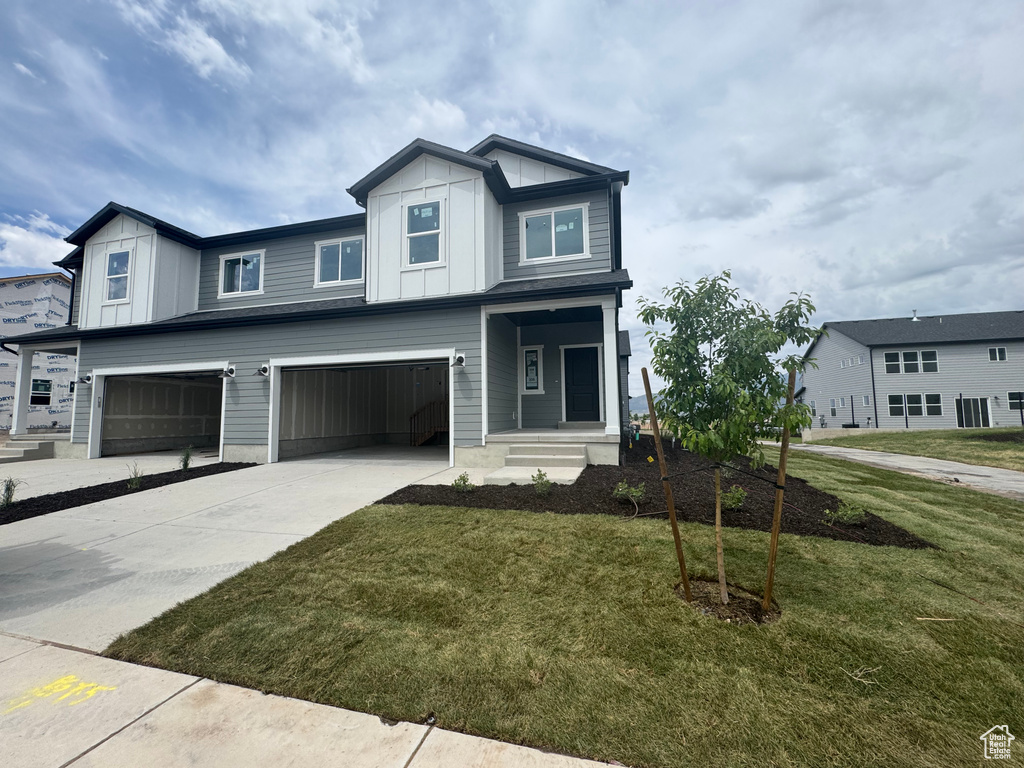 View of front facade with a garage, board and batten siding, and a front lawn
