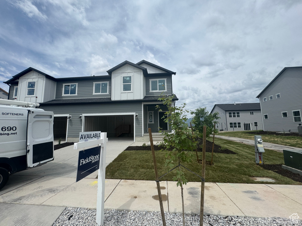 View of front of property featuring driveway, an attached garage, board and batten siding, and a front lawn