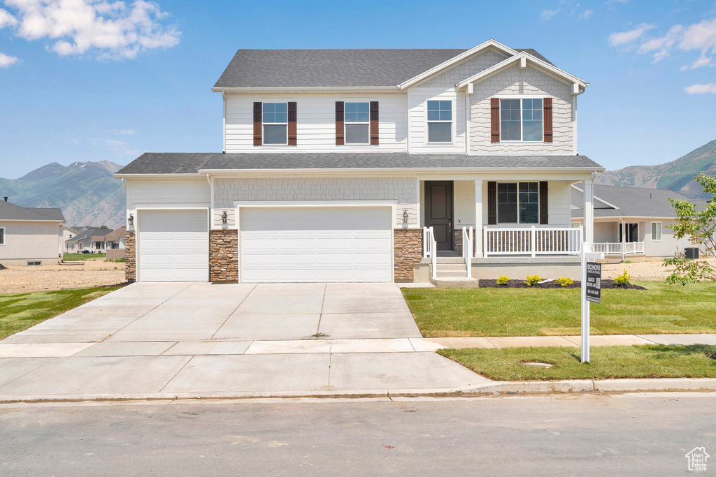 View of front of property with covered porch, a mountain view, a front lawn, and driveway