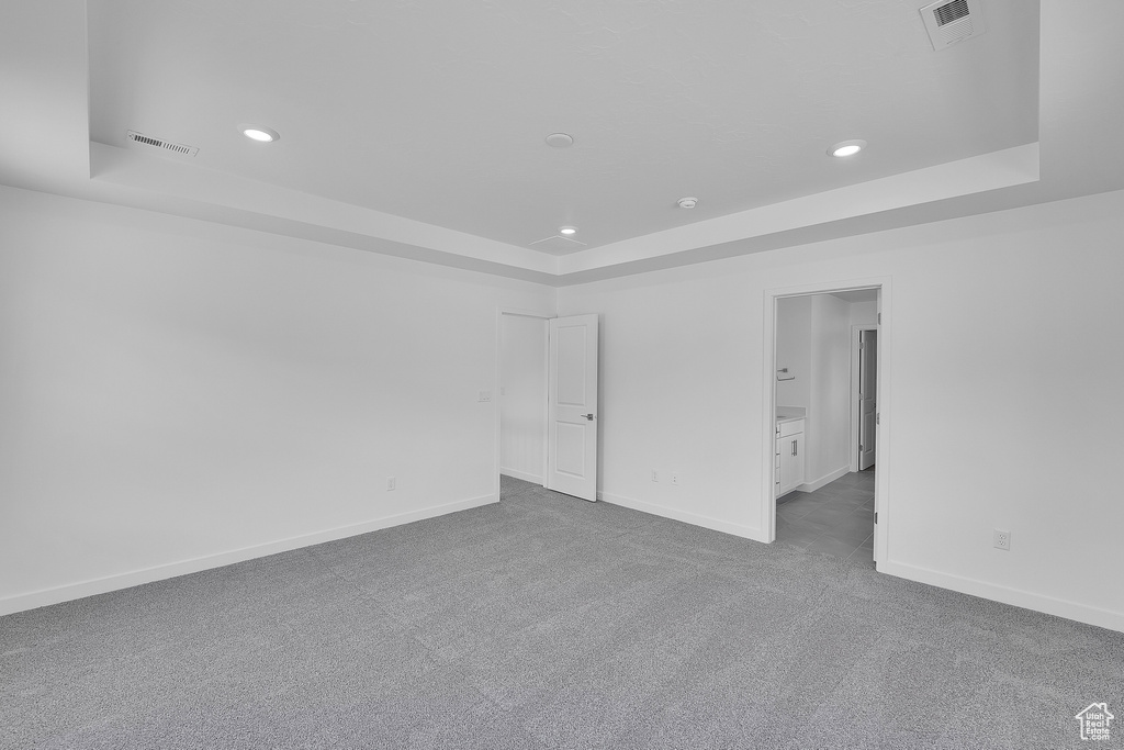 Spare room featuring a raised ceiling, carpet floors, recessed lighting, and baseboards