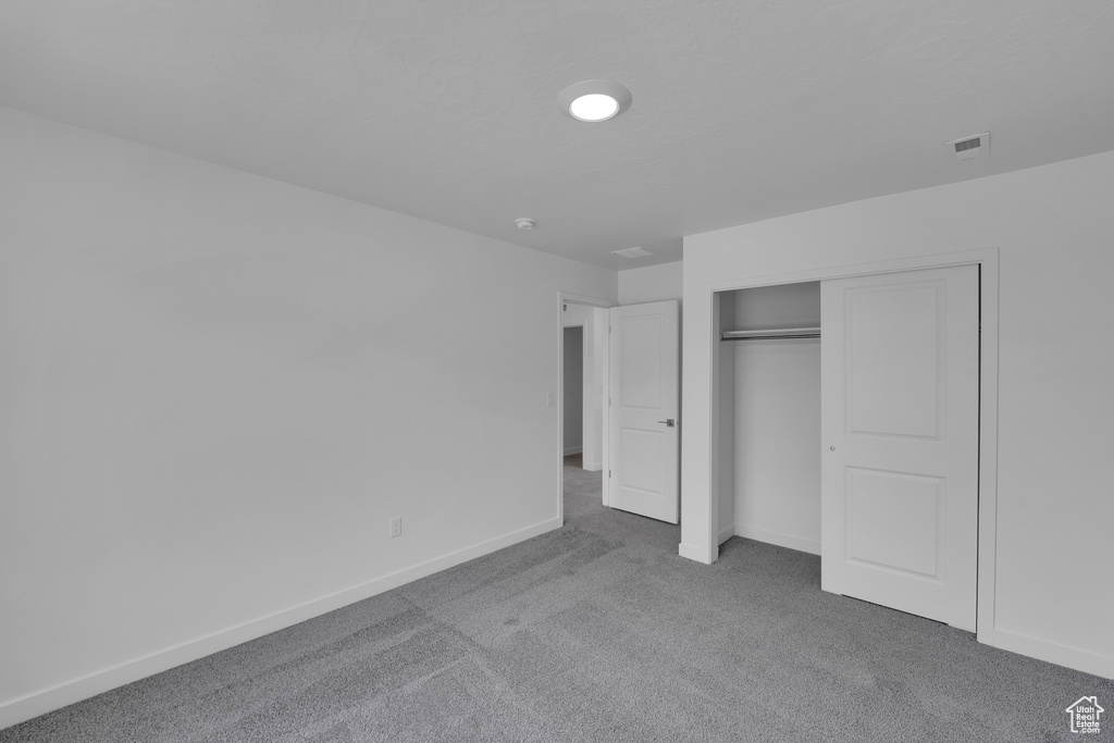 Unfurnished bedroom featuring carpet, a closet, and baseboards