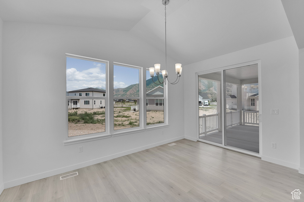 Unfurnished dining area featuring a chandelier, lofted ceiling, wood finished floors, and baseboards