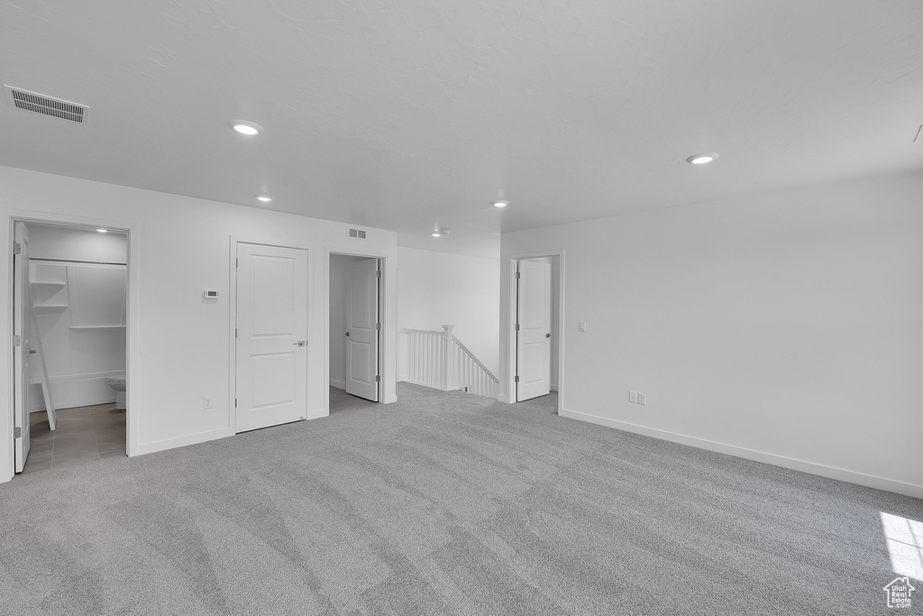 Unfurnished bedroom featuring carpet, recessed lighting, baseboards, and a walk in closet