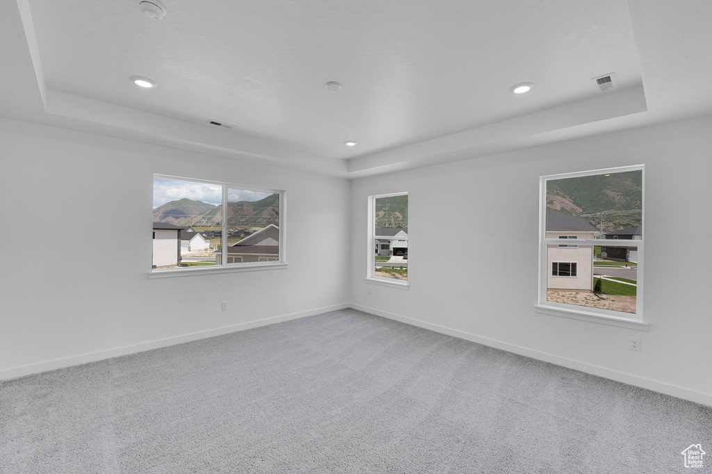 Carpeted empty room featuring a tray ceiling, baseboards, recessed lighting, and a smoke detector