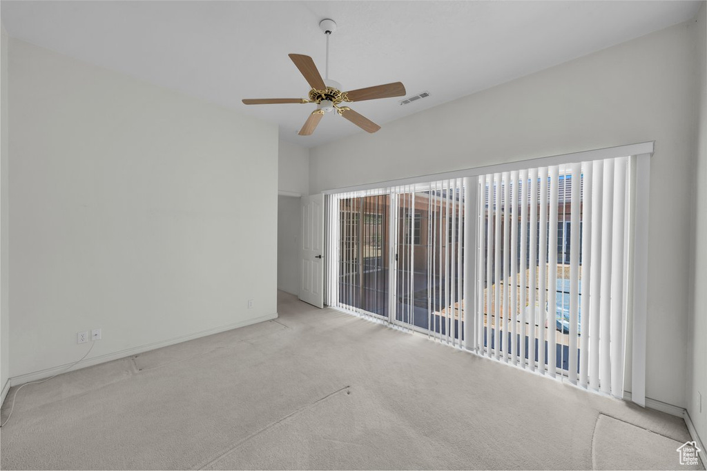 Carpeted spare room featuring healthy amount of natural light, a ceiling fan, and baseboards