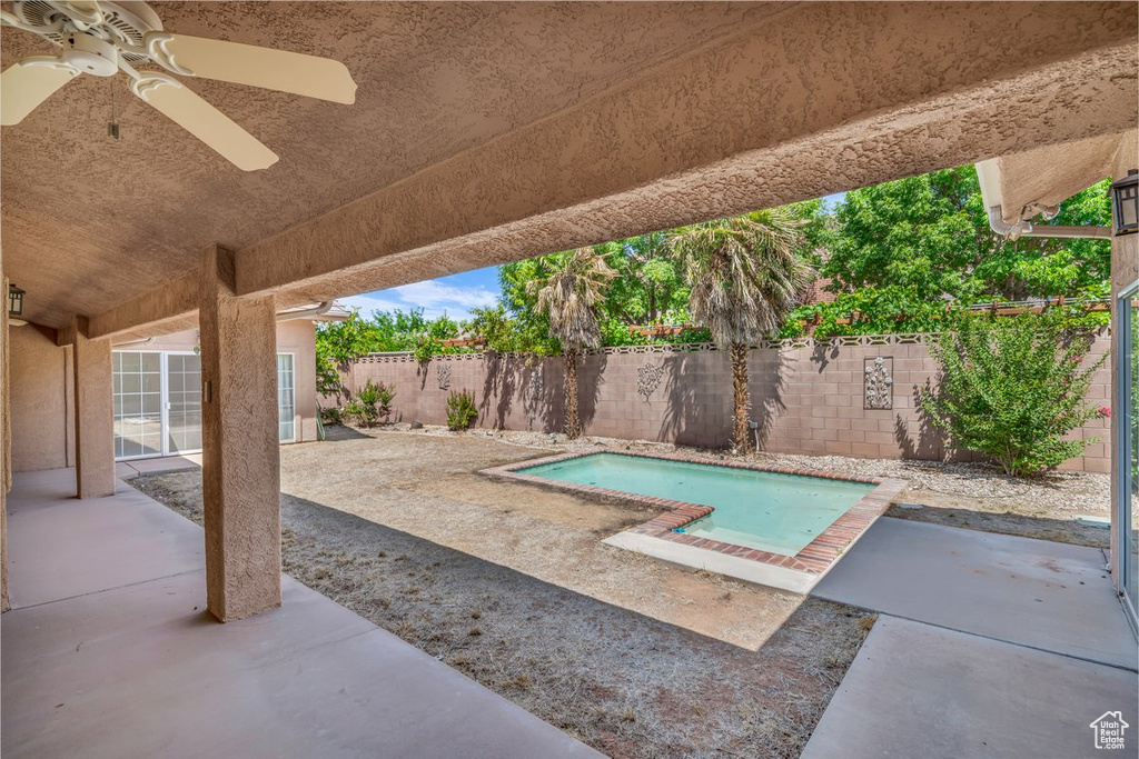 View of swimming pool with a fenced backyard, a ceiling fan, and a patio