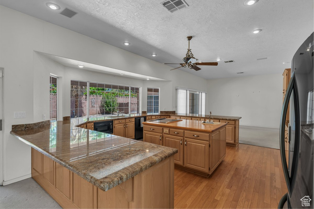 Kitchen featuring freestanding refrigerator, a sink, a peninsula, ceiling fan, and recessed lighting
