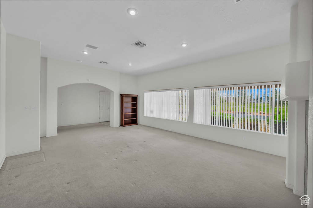 Carpeted empty room with arched walkways and recessed lighting