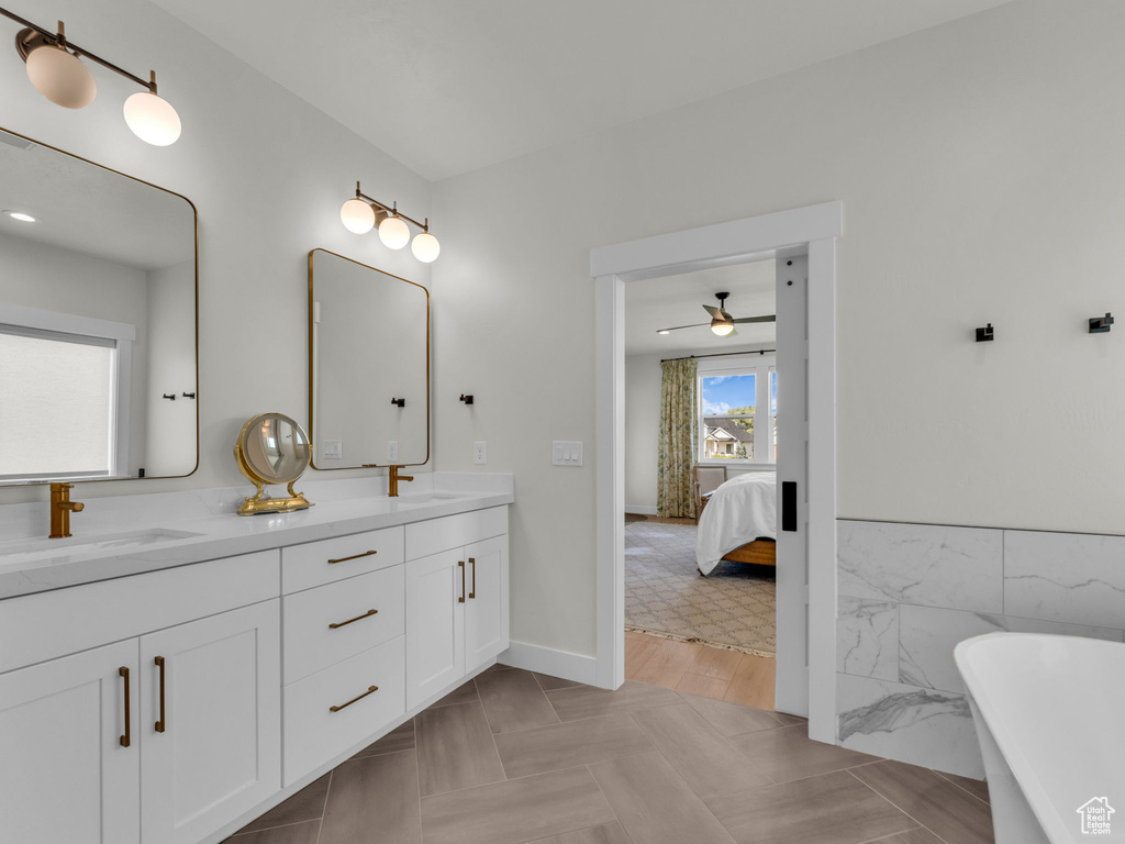 Ensuite bathroom with double vanity, a freestanding bath, and a ceiling fan