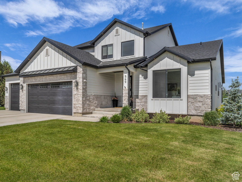 Modern farmhouse style home featuring a standing seam roof, board and batten siding, driveway, and a front lawn