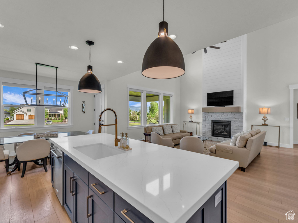 Kitchen featuring a sink, healthy amount of natural light, light wood-type flooring, recessed lighting, and a high ceiling